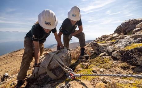 two people moving a rock off a hiking trail